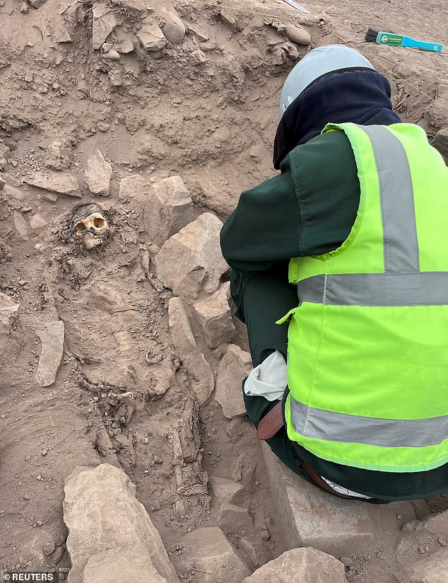 The head of mummy and the outline of the whole body are seen as an archaeologist works at the excavation site of a pre-Hispanic burial