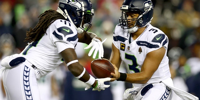 Russell Wilson hands the ball off to Alex Collins