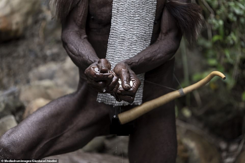A Dani tribesman wearing a Koteka, commonly known as a penis sheath, while he makes salt. Photographer Gianluca Chiodini, 41, spent days finding the isolated mountain tribe