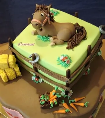 Cute horse laying down in a field with bales of hay cake