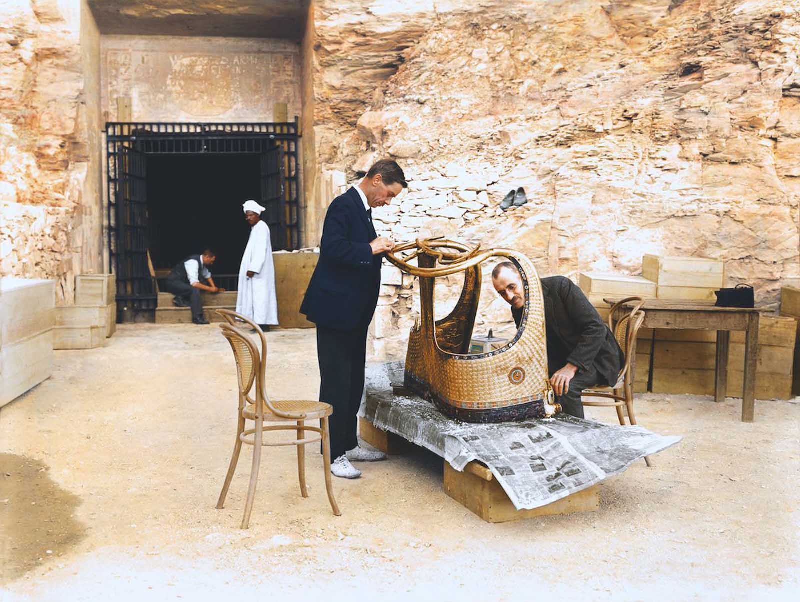 Arthur Mace and Alfred Lucas work on a golden chariot from Tutankhamun's tomb outside the