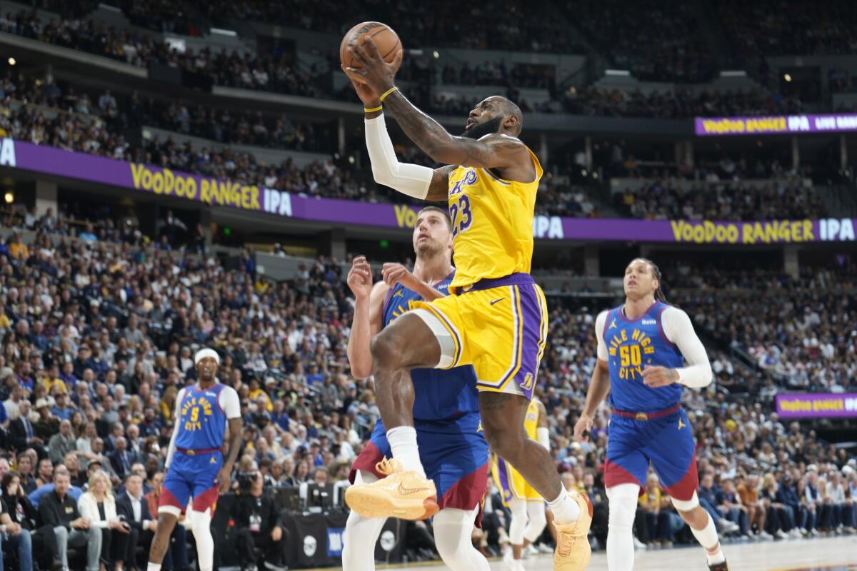 Lakers forward LeBron James drives to the basket past Denver Nuggets center Nikola Jokic and forward Aaron Gordon.