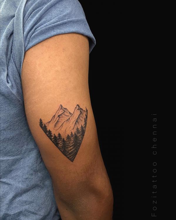 Mountain range and trees back of arm tattoo