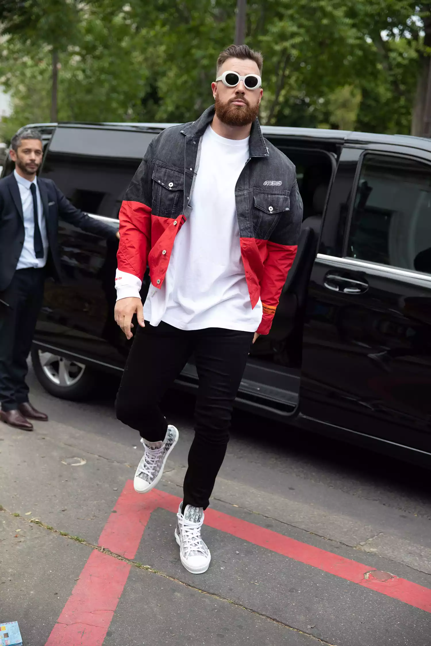 Travis Kelce, NFL Football player, wears a Heron Preston jacket and white Dior sneakers at the Heron Preston show at Palais de Tokyo on June 18, 2019 in Paris, France