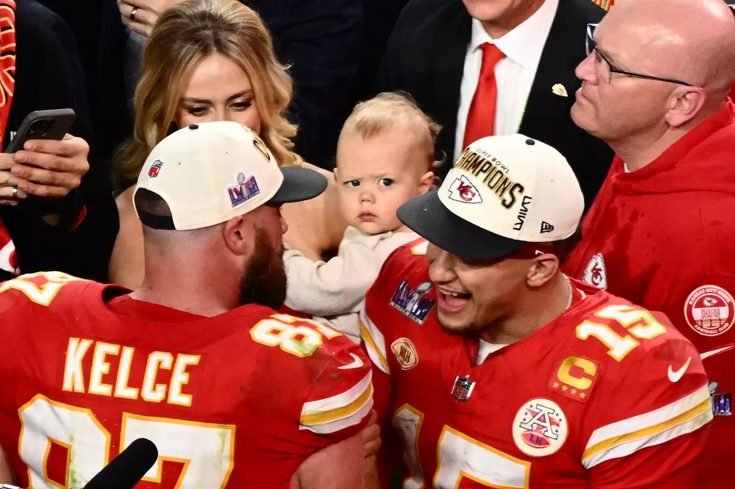 Kansas City Chiefs' quarterback #15 Patrick Mahomes (R) speaks to Kansas City Chiefs' tight end #87 Travis Kelce as his wife Brittany Mahomes holds his son Patrick Bronze after the Chiefs won Super Bowl LVIII against the San Francisco 49ers at Allegiant Stadium in Las Vegas, Nevada, February 11, 2024.