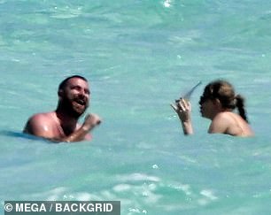 The lovebirds couldn't contain their smiles during the beach day, with Travis seen animatedly laughing at something Taylor told him