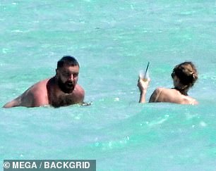 The lovebirds couldn't contain their smiles during the beach day, with Travis seen animatedly laughing at something Taylor told him