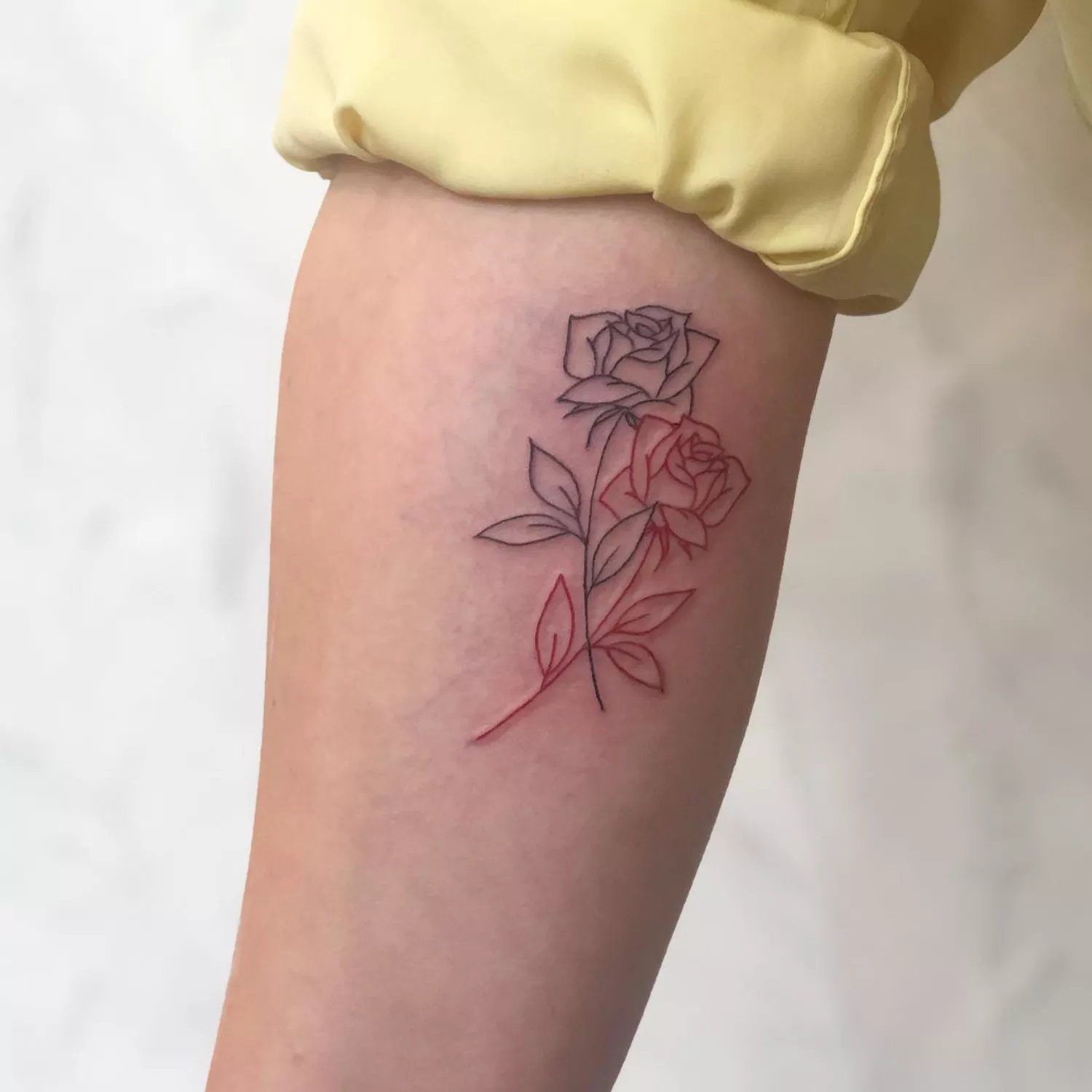 A close up of a forearm with a two-tone rose tattoo.