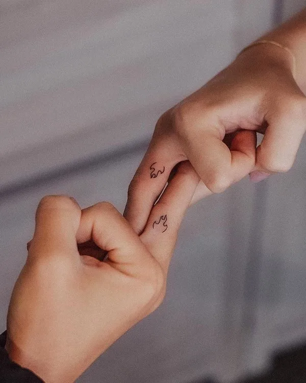 Small matching fire symbol finger tattoos by @tavi_tattoo