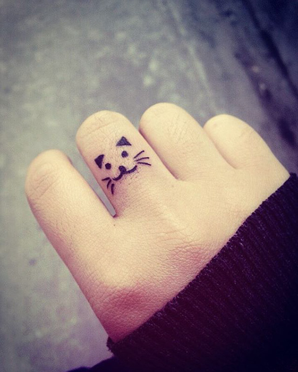 Cat face tattoo on middle finger