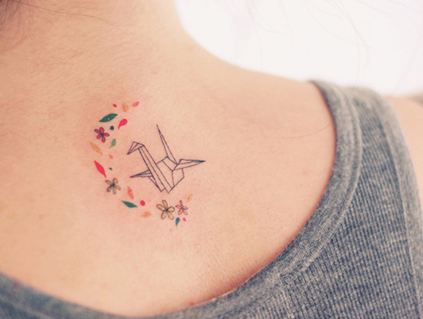 Origami crane, small colorful flowers and leaves tattoo on the back