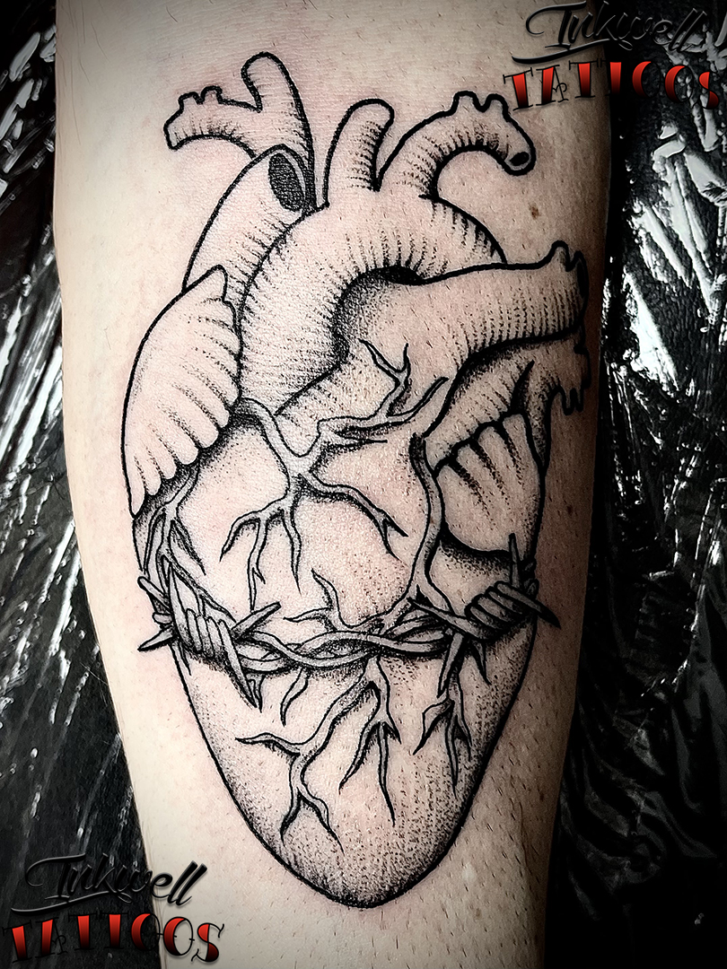 Real heart wrapped in barbed wire tattoo