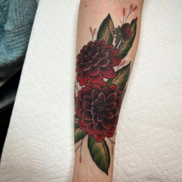 Two deep red dahlia tattoo on forearm