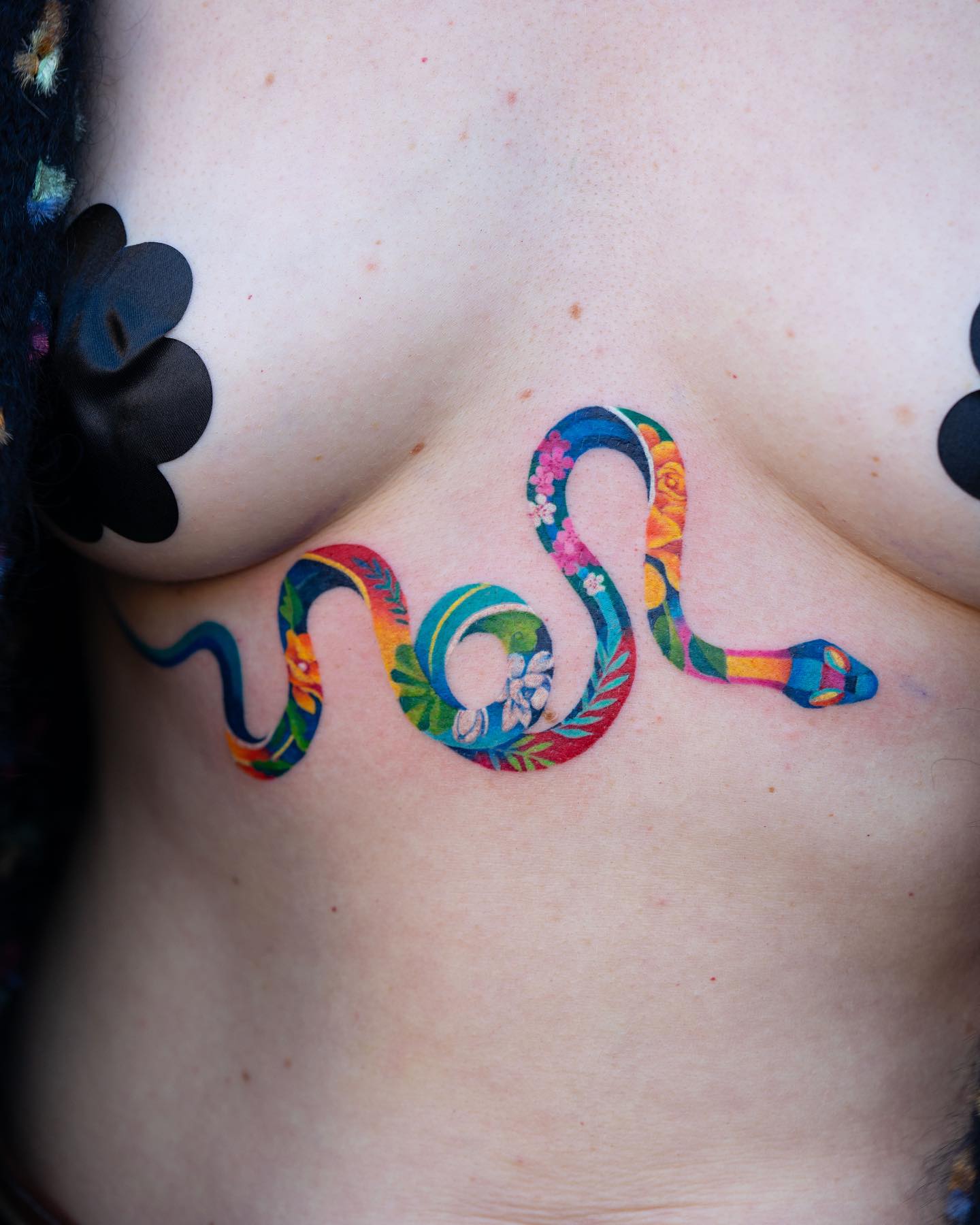 Colorful floral snake tattoo under the boob, watercolor style