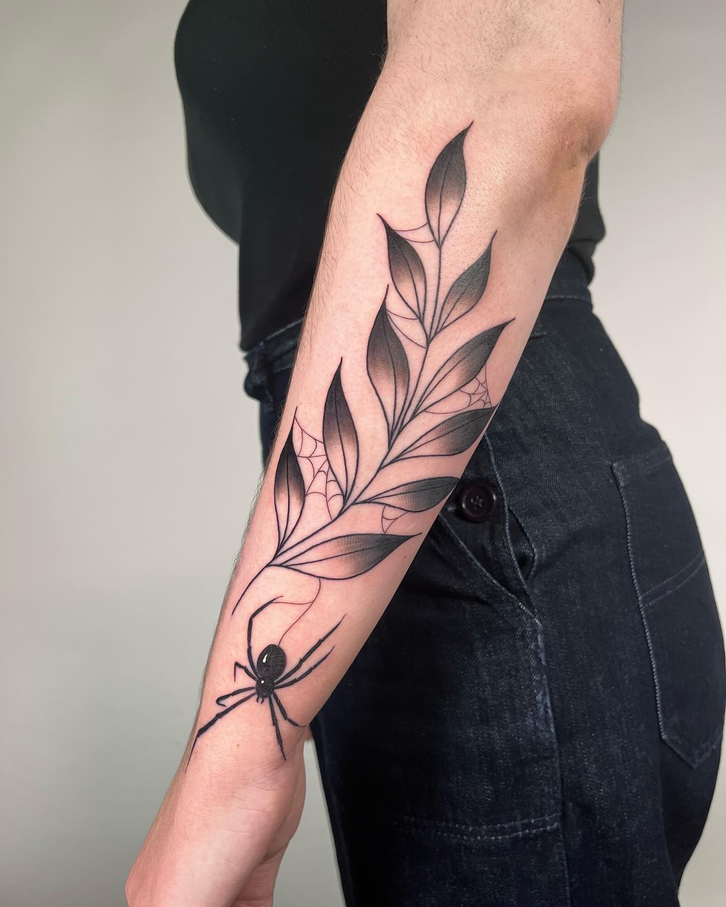 Leaves cannot be imagined without animals on them, can they? To give botanical vibe on your arm with your tattoo, some leaves that are covered in a spider's web and a spider below are all you need.