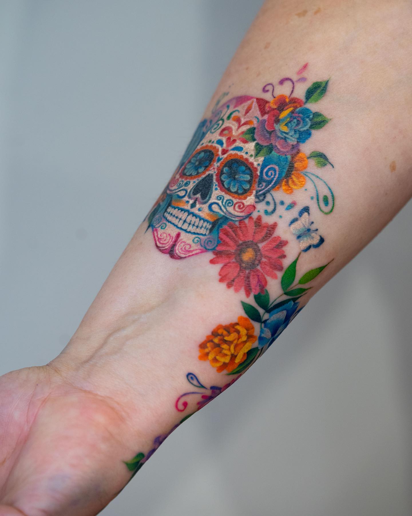 Skull and flowers tattooed on the wrist and forearm