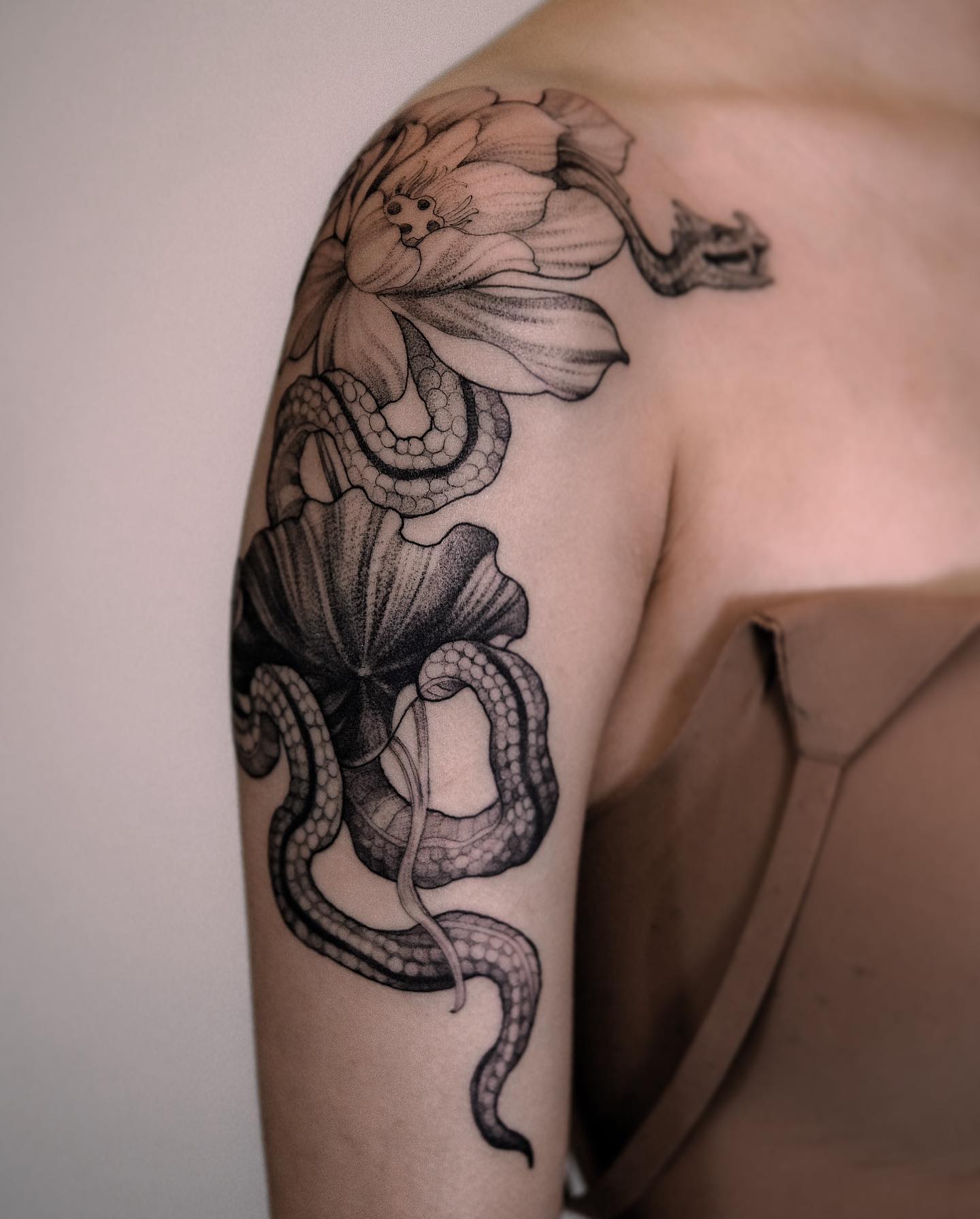 Snake and flowers tattooed on the upper arm