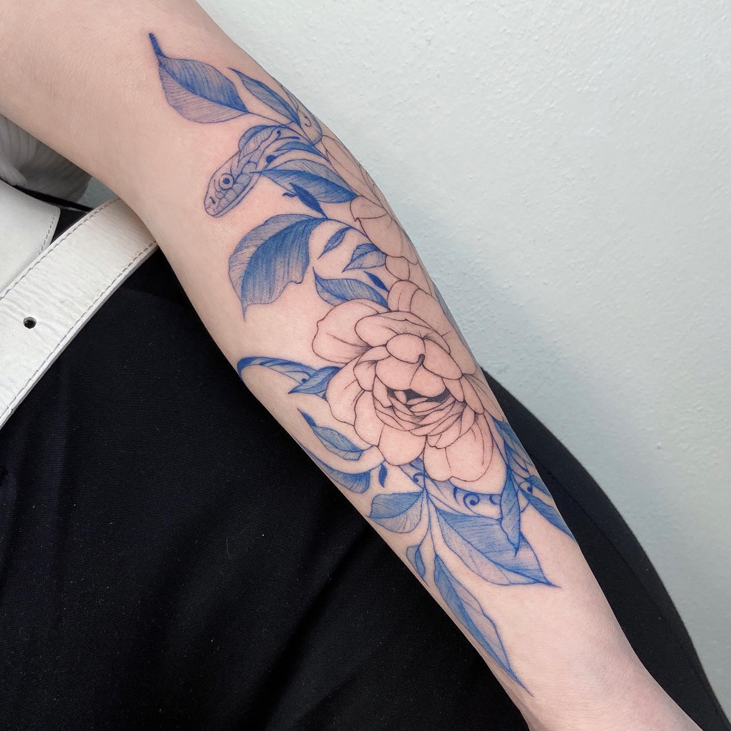 Peony and porcelain snake tattooed on the forearm