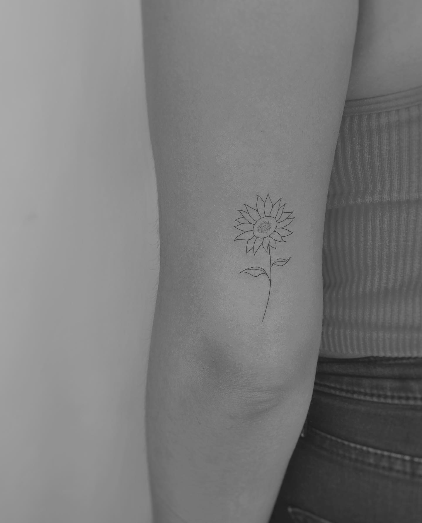 Fine line style sunflower tattoo on the outer arm