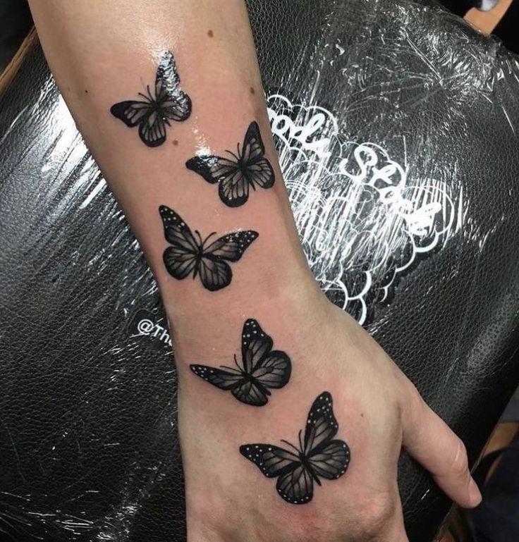 This may contain: a woman's hand with black butterflies on the left side of her arm and wrist