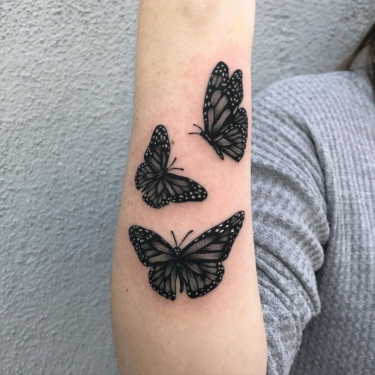 This may contain: three black butterflies on the arm