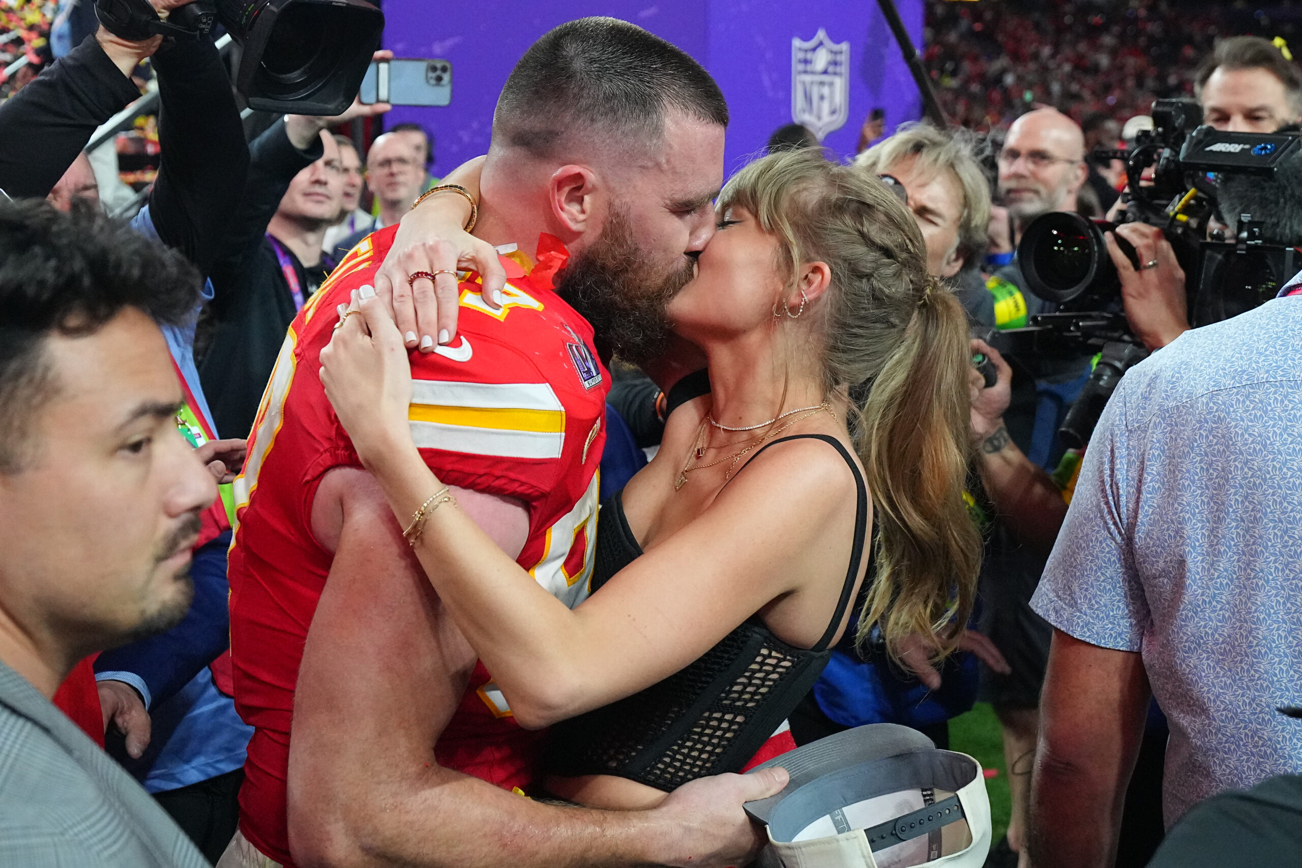 Travis Kelce and Taylor Swift kissing at a football game