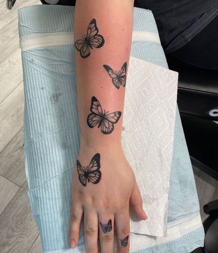 This may contain: a woman's arm with three butterflies tattooed on the left side of her hand