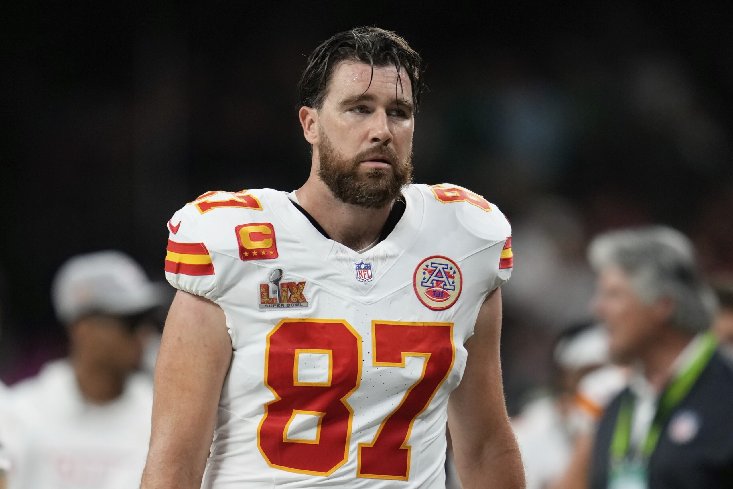 Travis Kelce during the Super Bowl LIX halftime break. His brown hair is sweaty and he looks tired. He is wearing his white, red and yellow jersey.