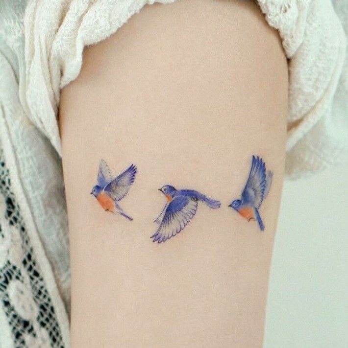 This may contain: three small birds on the back of a woman's thigh, flying away from each other