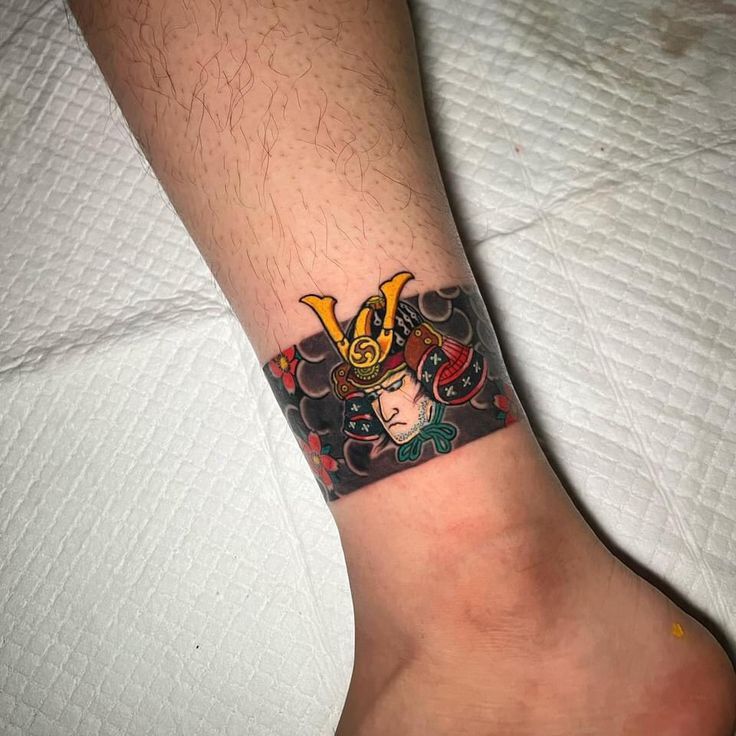 Ankle tattoo of an angry man's face, showing strength and determination