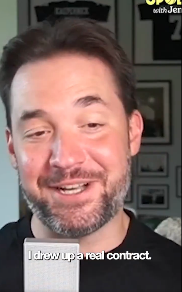 A person with short hair and a beard is smiling, speaking into a microphone. Text on image: "I drew up a real contract."