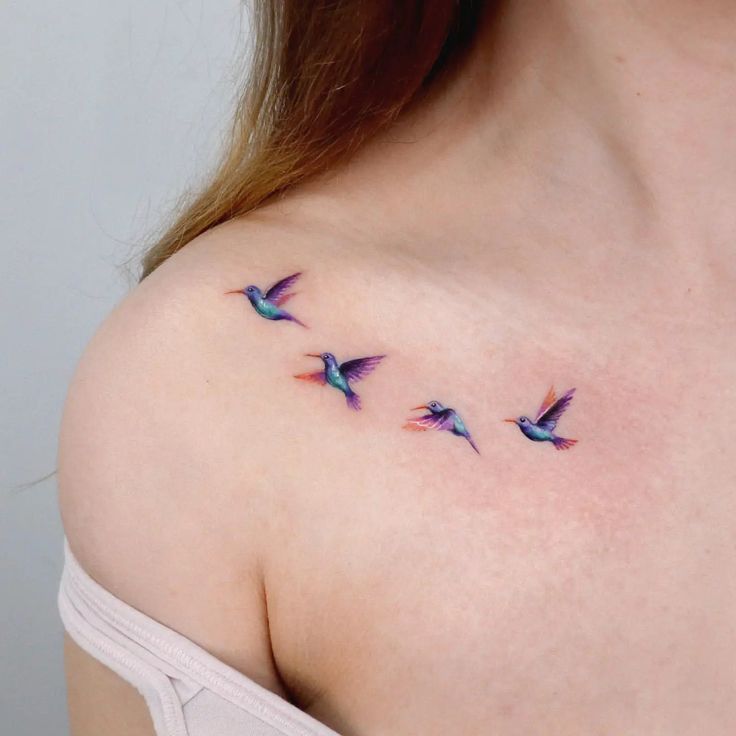 This may contain: a woman's shoulder with three small birds on the left side of her chest