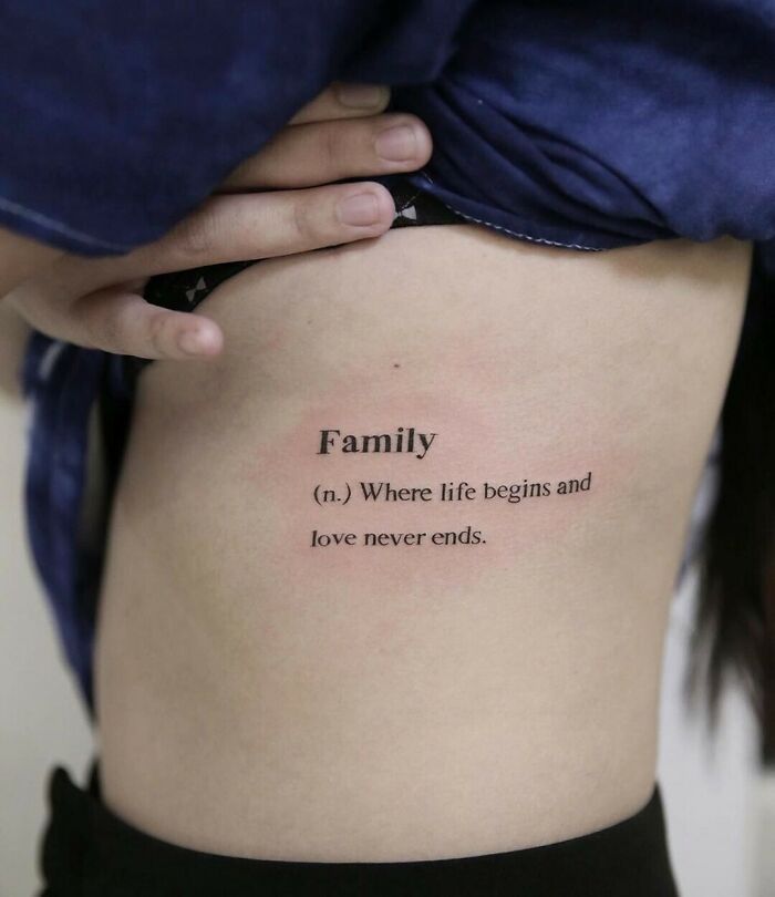 Tattoo of the word "Family" with a meaningful quote on a person's side, symbolizing unbreakable family bonds. Tattoo of the word "Family" with a meaningful quote on a person's side, symbolizing unbreakable family bonds.