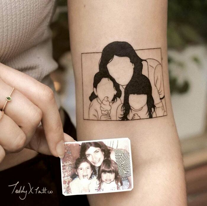 Family tattoo depicting a mother and children, symbolizing unbreakable bonds, with a matching photo held beside it. Family tattoo depicting a mother and children, symbolizing unbreakable bonds, with a matching photo held beside it.