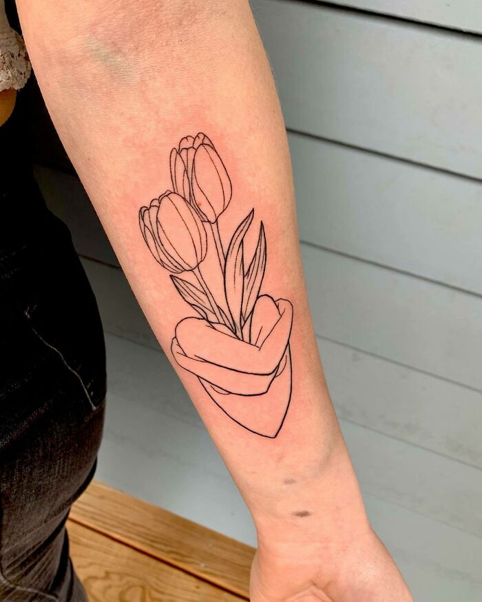 Tulip tattoo on forearm symbolizing family bonds, featuring two flowers held by a heart-shaped hand. Tulip tattoo on forearm symbolizing family bonds, featuring two flowers held by a heart-shaped hand.