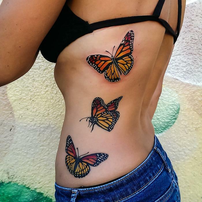 Colorful butterfly tattoos on a person's side, showcasing vibrant and detailed designs. Colorful butterfly tattoos on a person's side, showcasing vibrant and detailed designs.