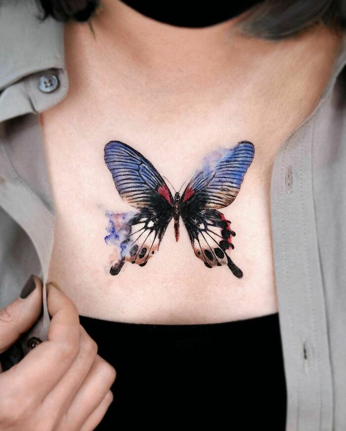 Colorful butterfly tattoo on a person's chest, featuring vibrant blue and red hues. Colorful butterfly tattoo on a person's chest, featuring vibrant blue and red hues.