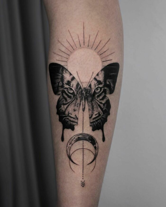 Minimalist butterfly tattoo with celestial elements on forearm, showcasing intricate black ink design. Minimalist butterfly tattoo with celestial elements on forearm, showcasing intricate black ink design.