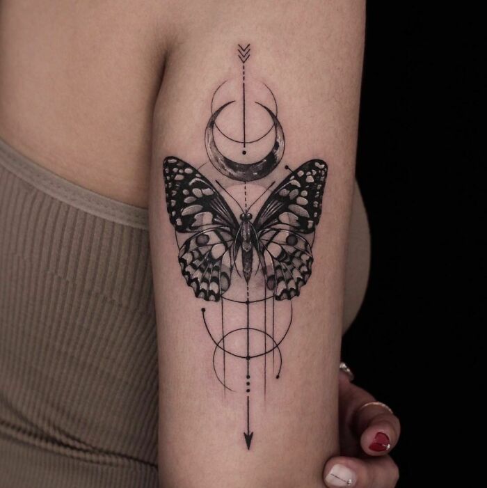 Black and white butterfly tattoo on arm with geometric design elements, showcasing intricate detail. Black and white butterfly tattoo on arm with geometric design elements, showcasing intricate detail.