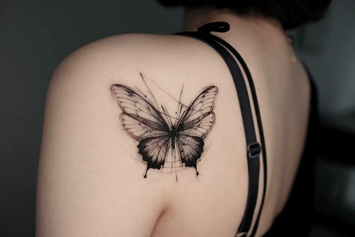 Butterfly tattoo on shoulder in black ink, showcasing detailed wing patterns. Butterfly tattoo on shoulder in black ink, showcasing detailed wing patterns.