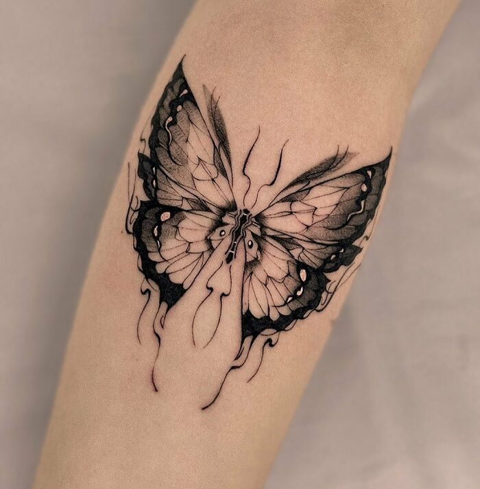 Black and white butterfly tattoo on forearm, showcasing intricate and artistic design. Black and white butterfly tattoo on forearm, showcasing intricate and artistic design.