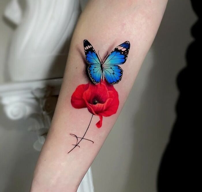 A colorful butterfly tattoo with blue wings and a red flower on an arm. A colorful butterfly tattoo with blue wings and a red flower on an arm.