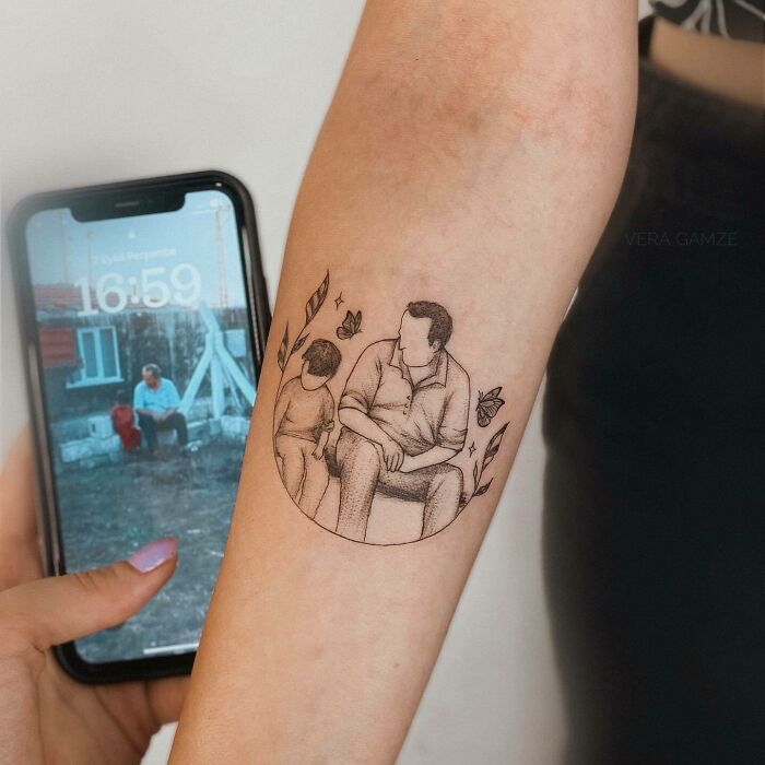 Tattoo of a father and child, symbolizing family bonds, next to a matching photo displayed on a smartphone screen. Tattoo of a father and child, symbolizing family bonds, next to a matching photo displayed on a smartphone screen.