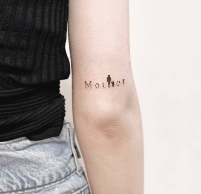 Tattoo on arm reading "Mother" symbolizing family bonds with silhouette figures, expressing unbreakable connections. Tattoo on arm reading "Mother" symbolizing family bonds with silhouette figures, expressing unbreakable connections.