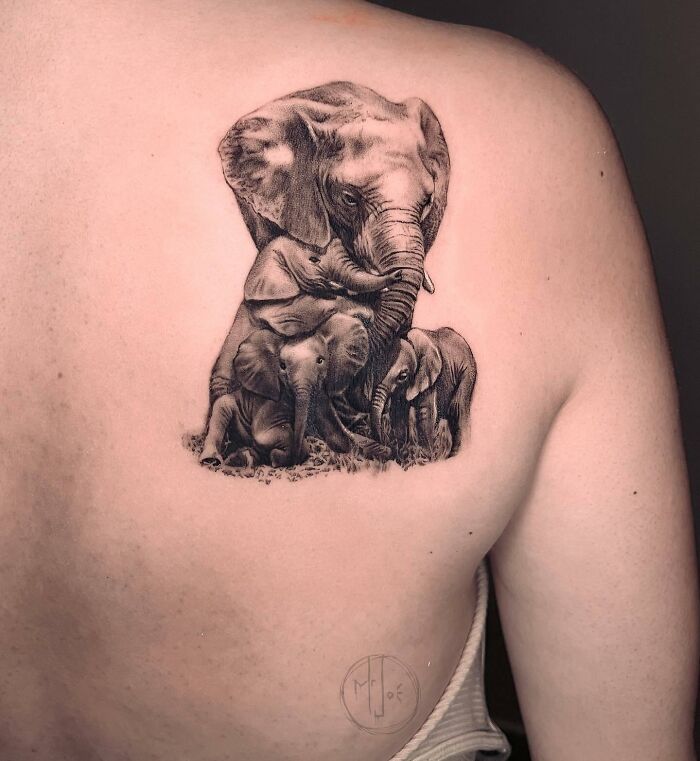 Elephant family tattoo symbolizing unbreakable bonds on a person's back. Elephant family tattoo symbolizing unbreakable bonds on a person's back.