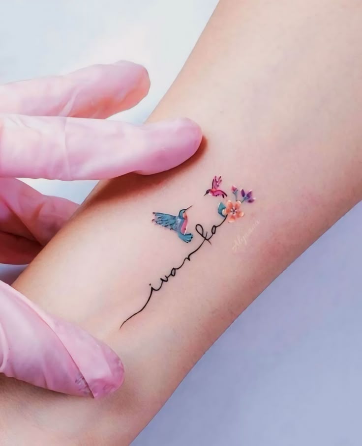 This may contain: a person with a tattoo on their arm holding onto another persons hand and the word love is written in small flowers