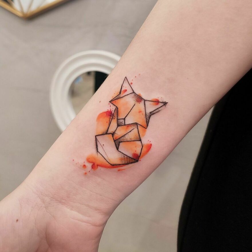 Geometric fox watercolor tattoo with orange accents on forearm. Geometric fox watercolor tattoo with orange accents on forearm.