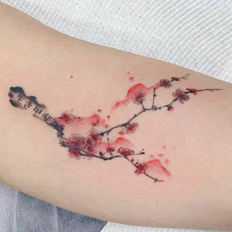 Watercolor tattoo of cherry blossoms with delicate red and black ink on skin. Watercolor tattoo of cherry blossoms with delicate red and black ink on skin.