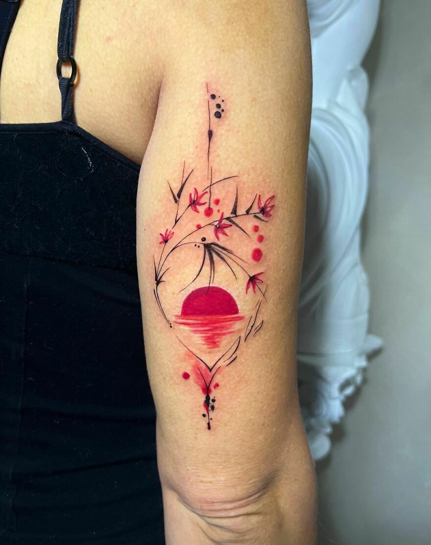 Watercolor tattoo on arm featuring a red sun with delicate floral designs. Watercolor tattoo on arm featuring a red sun with delicate floral designs.