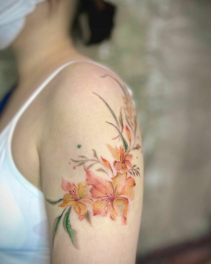 Watercolor tattoo of orange flowers on an arm, showcasing delicate and artistic design elements. Watercolor tattoo of orange flowers on an arm, showcasing delicate and artistic design elements.